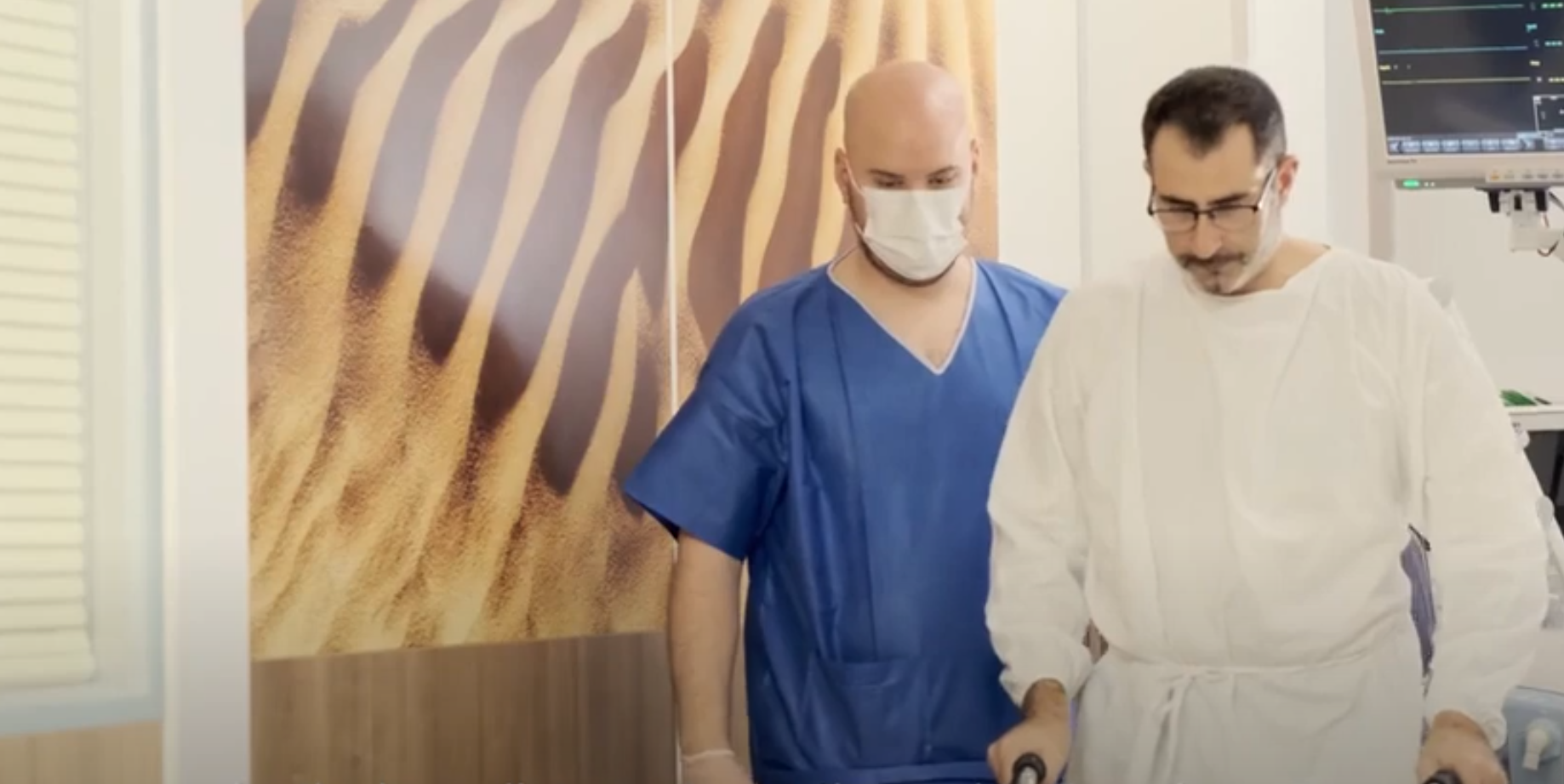 A patient walks with assistance from a nurse